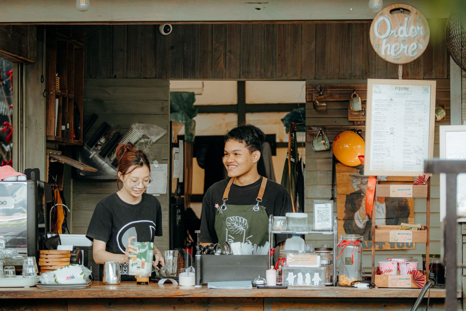 Two baristas smiling behind a café counter