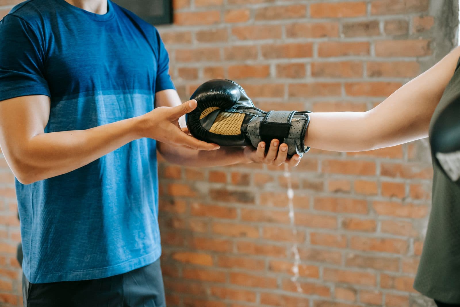 A trainer helps a gym member with boxing gloves