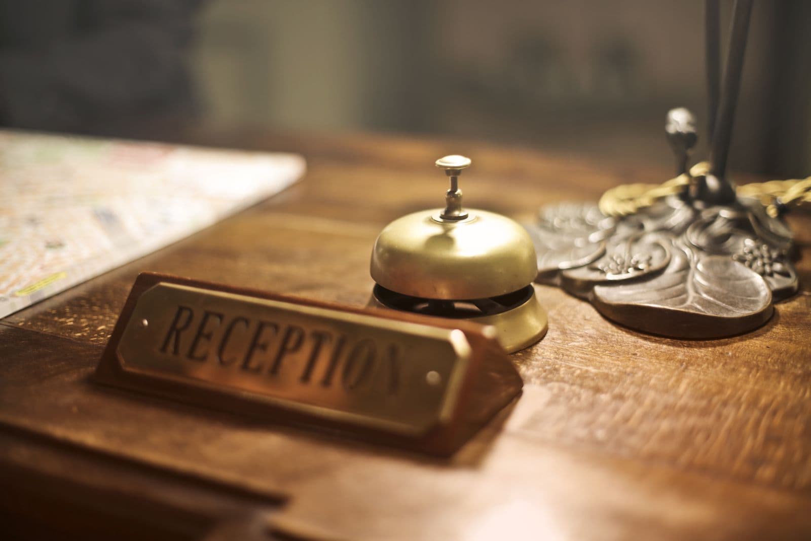 A reception bell and sign on a wooden hotel desk