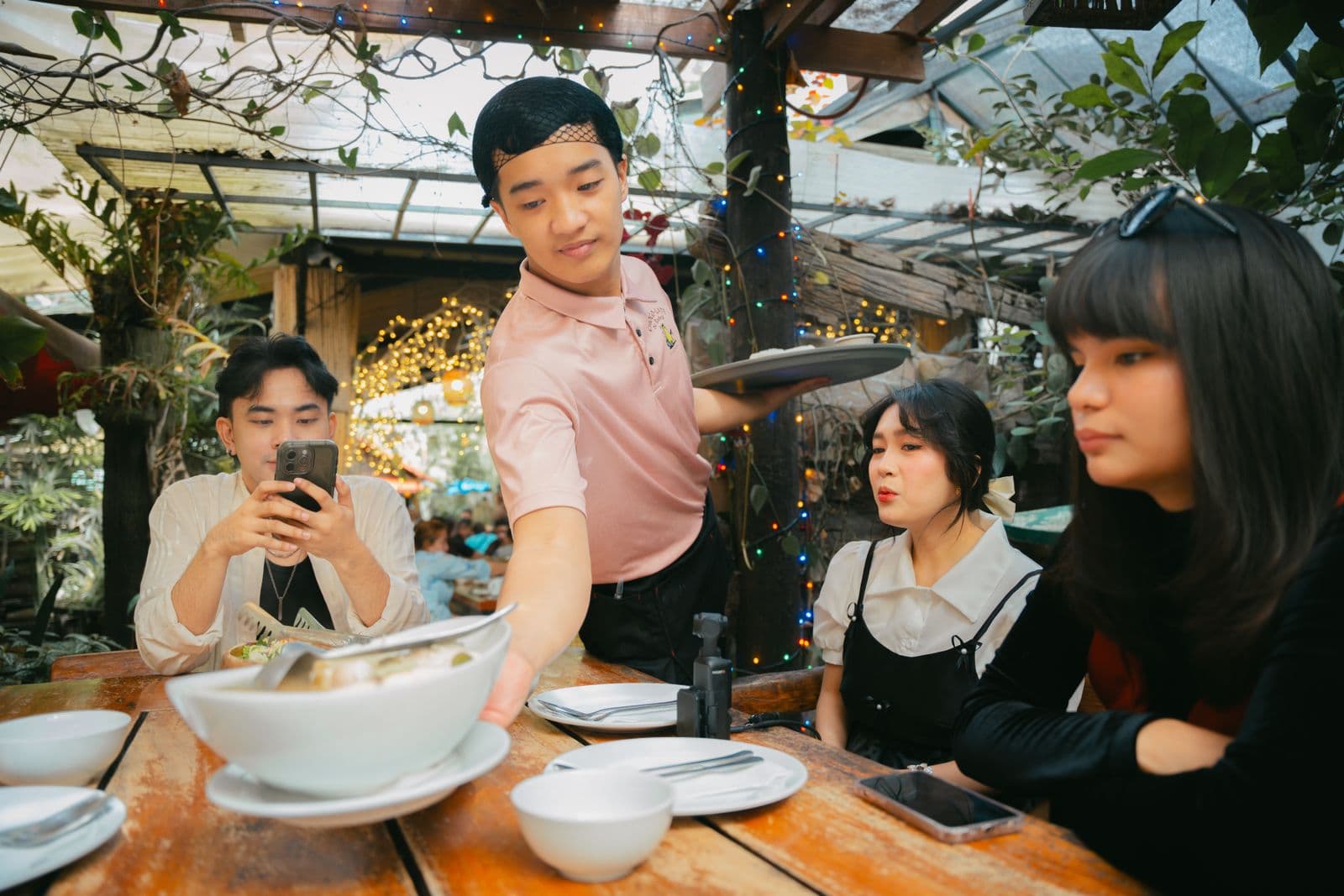 A waiter serves a table of friends at an outdoor restaurant
